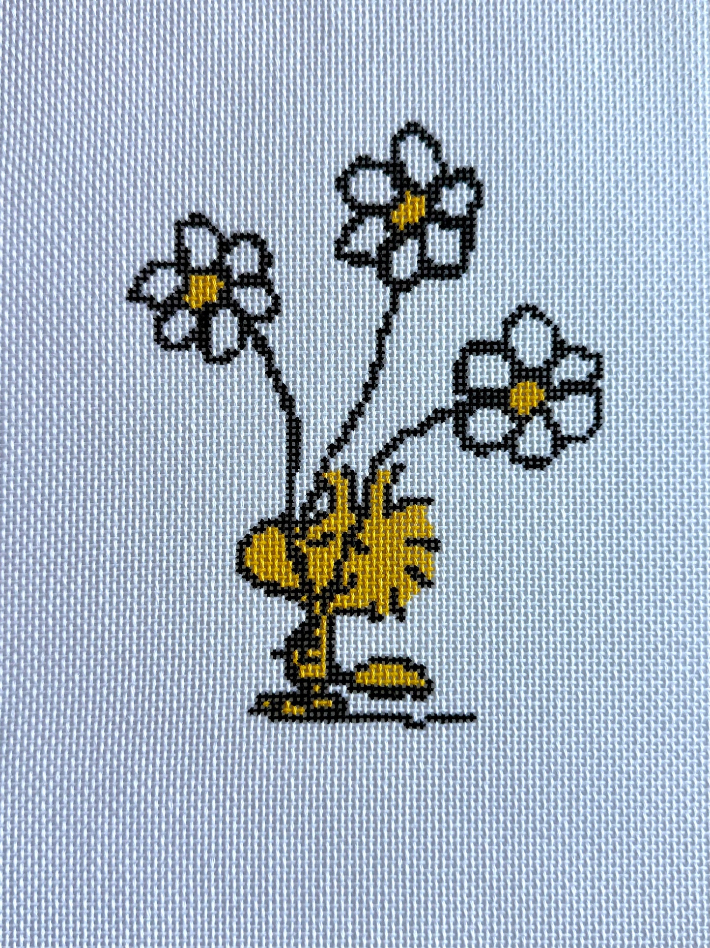 Needlepoint design of Peanuts Woodstock with three daisies on a white background of 18 mesh